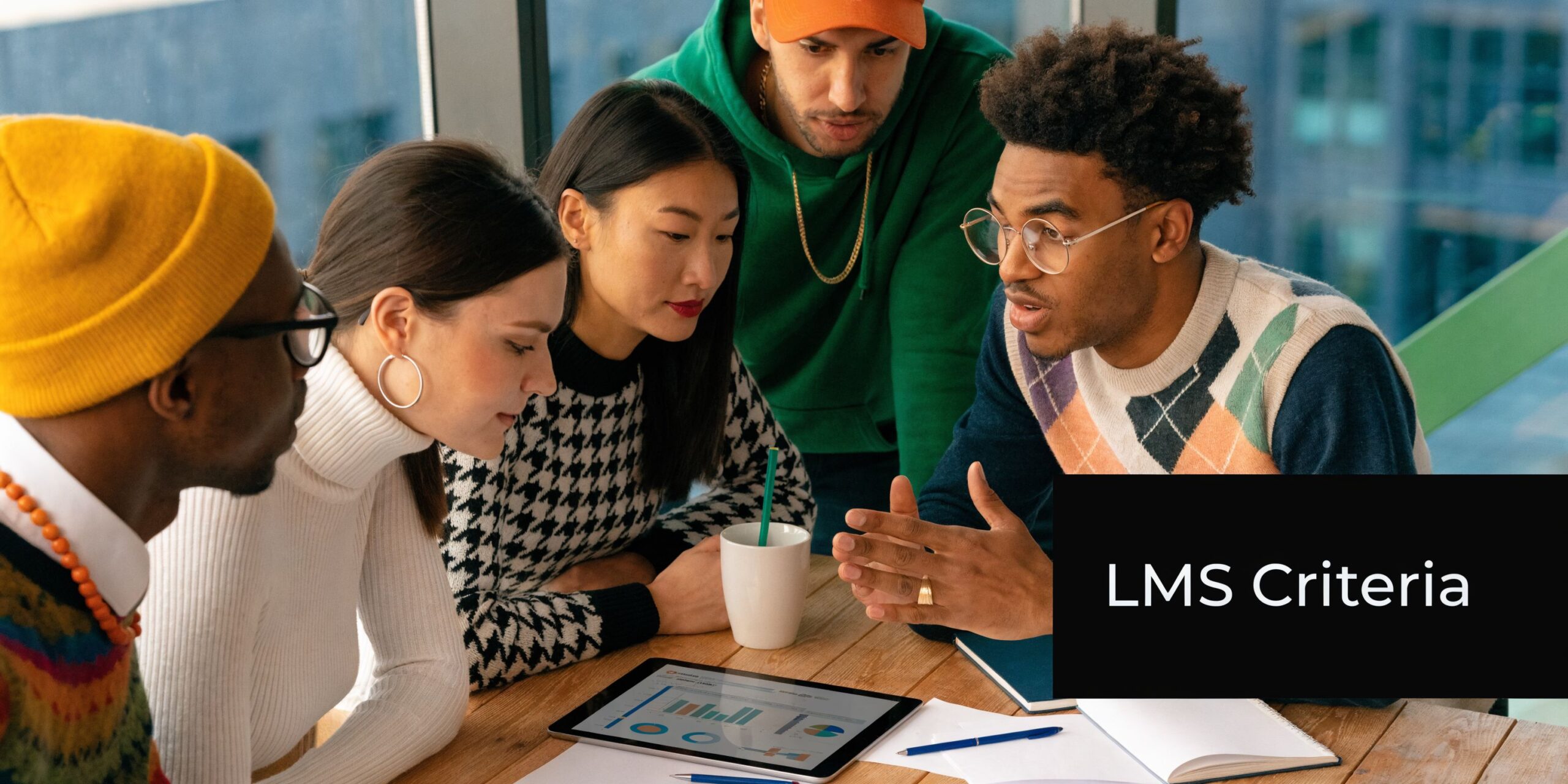 A diverse team of professionals collaboratively discussing business data on a tablet during a workspace meeting.