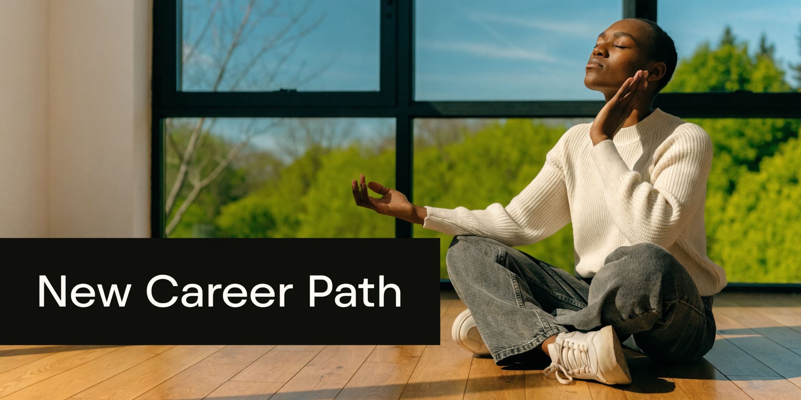A person sitting on a wooden floor in a lotus position, appearing calm and practicing mindfulness.